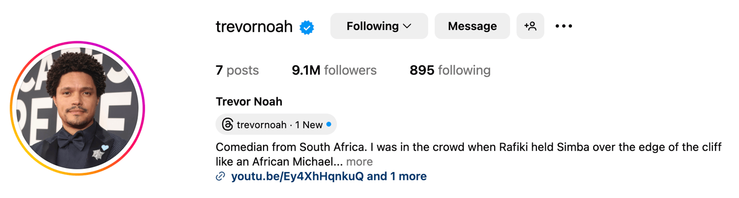 Trevor Noah wearing a tailored casual outfit against a simple stage backdrop.